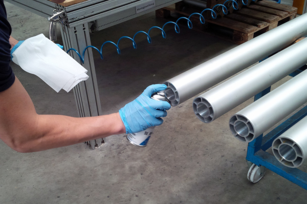 spray paint, hand with spray, metal tubes, industrial setting, workshop