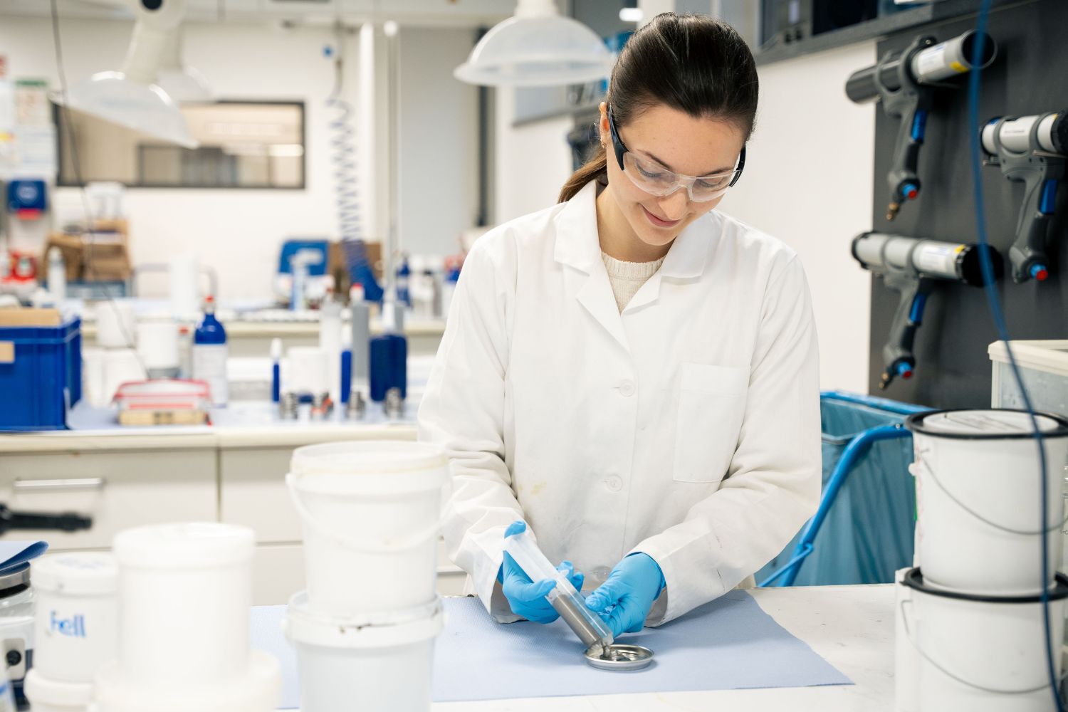 A woman in the laboratory pours a two-component adhesive into a metal lid